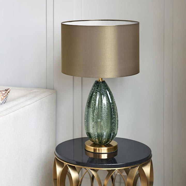 Stylish glass base table lamp in green, perfect for modern home decor, enhancing bedroom or living room lighting.