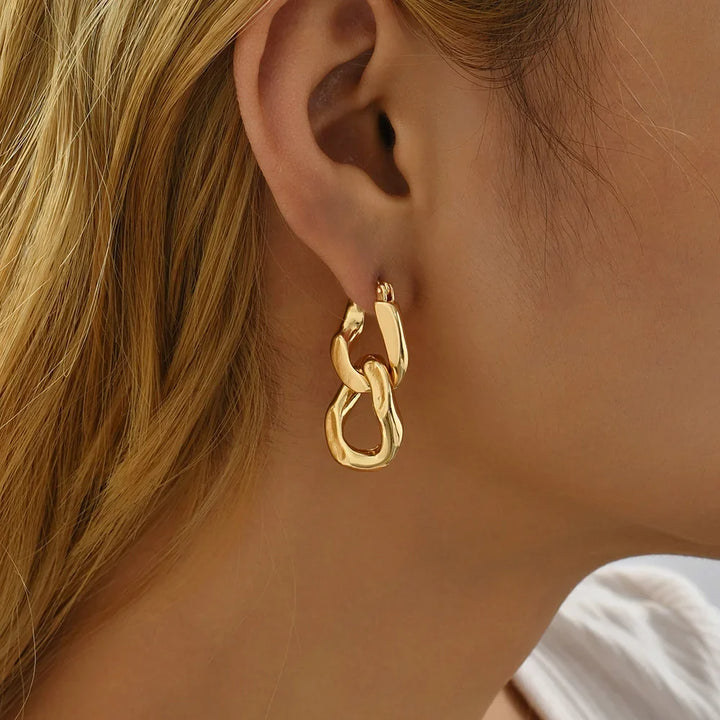 Close-up of women's modern chunky gold interlocking link earrings, highlighting polished finish and detail.