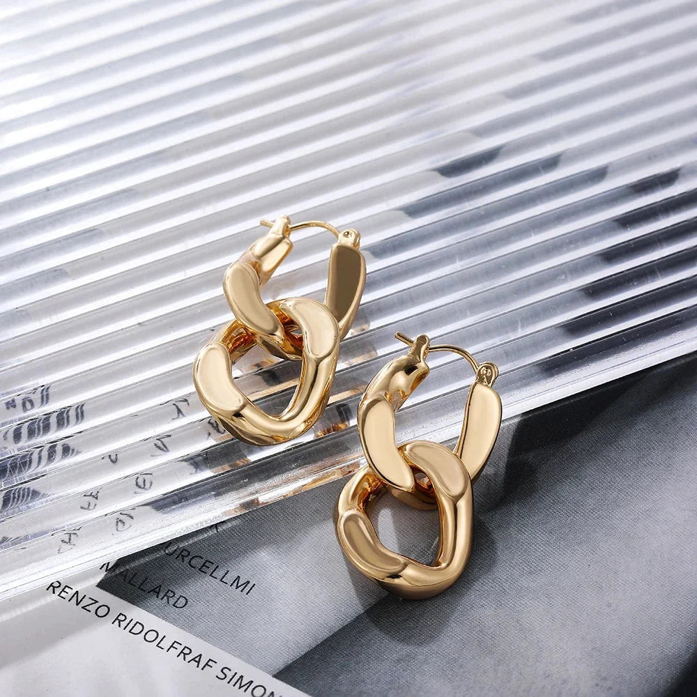 Women's modern interlocking gold link earrings worn, showcasing a stylish chunky statement accessory.