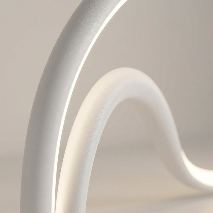 Close up of the Arcelle LED sculptural table lamp, showcasing its unique modern curved form and light.