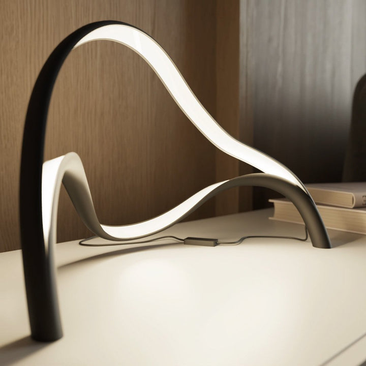 Contemporary Arcelle LED desk lamp providing efficient task lighting with its unique sculptural shape.