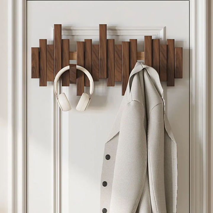 Minimalist natural wood wall hook rack with hidden, foldable hooks. A modern, space-saving solution for entryway organization.