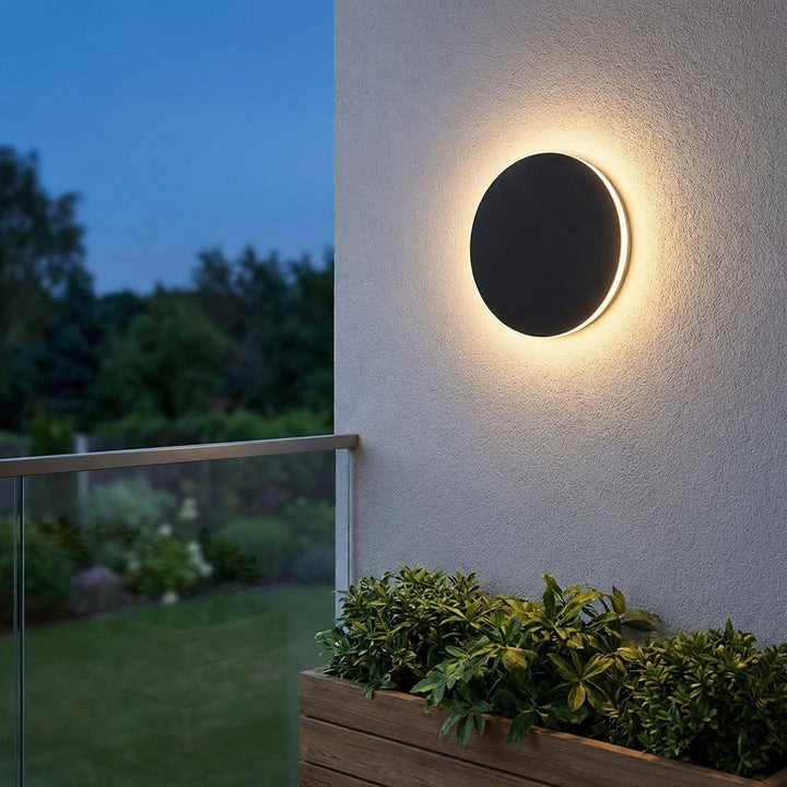 Modern outdoor round LED wall light by Solunex, stainless steel for ambient patio and garden lighting.