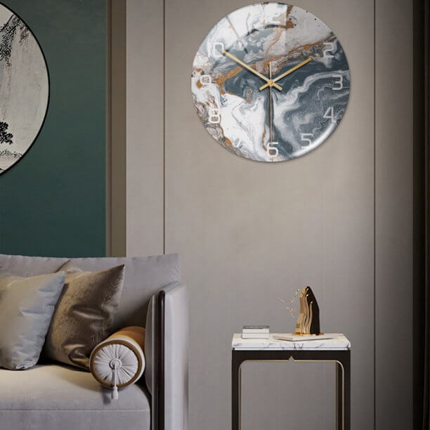 Modern accent round wall clock, faux marble finish, enhances contemporary decor.