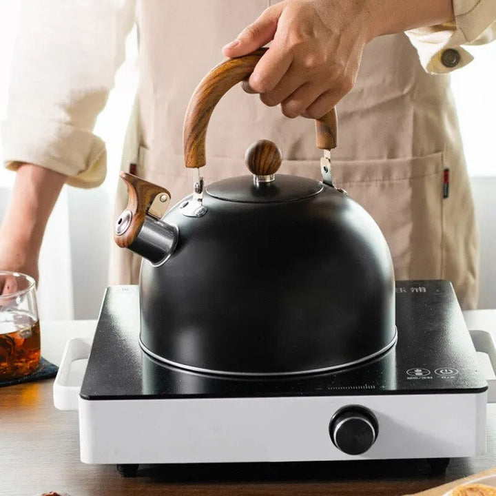 Ergonomic black handle and polished stainless steel body of a Kavana whistling tea kettle.