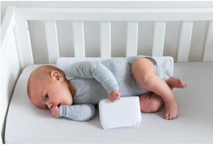Grey adjustable anti-roll baby side sleep pillow. Essential newborn infant care product for safe and supported sleep.