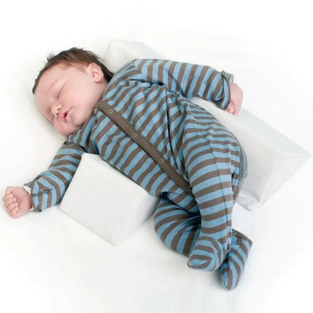 Peaceful newborn sleeping soundly on a safe side sleeper wedge, promoting infant rest.