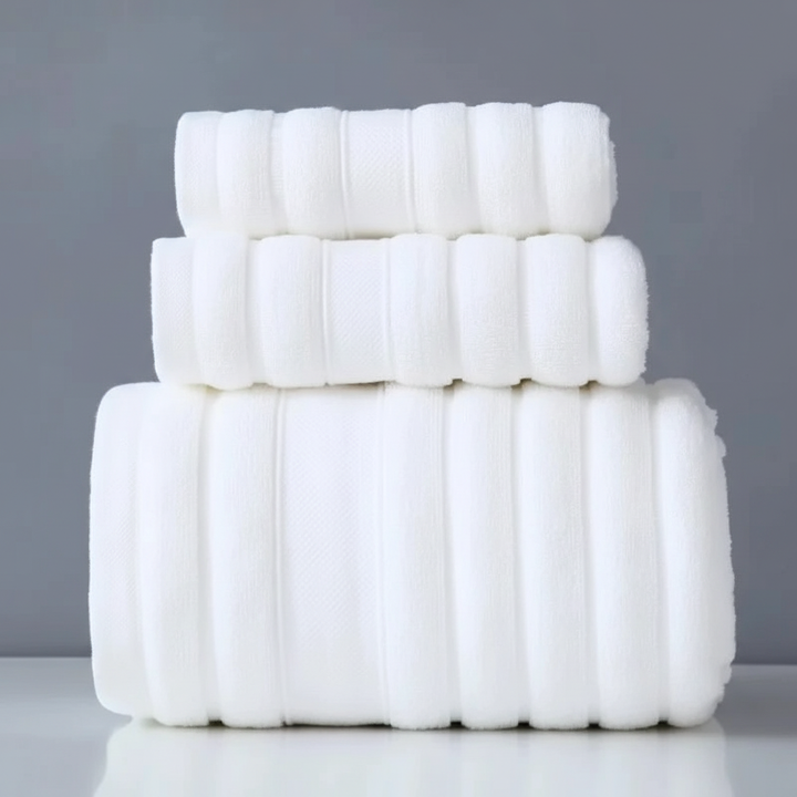 Stack of neatly folded CottonDream terry cotton towels, part of an indulgent set, emphasizing softness and absorbency