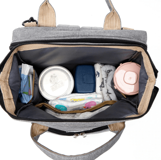 Grey baby travel backpack in use as a portable changing station with baby lying inside.