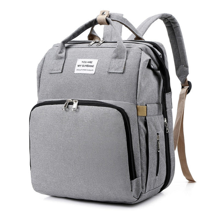 Multi-function baby bag for travel, expanding into a safe, soft portable bed with easy access storage.