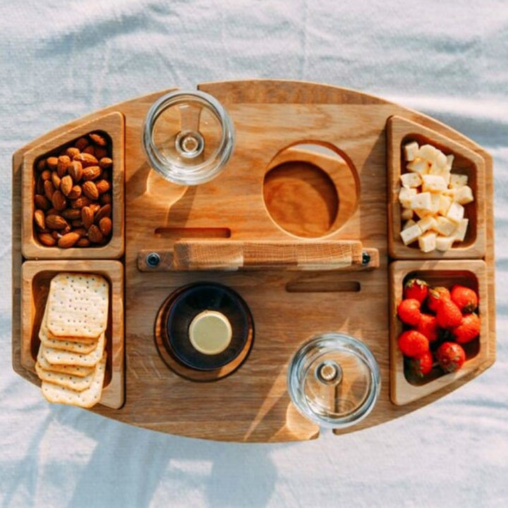 Folding picnic wine table with integrated holders for wine glasses & bottle.
