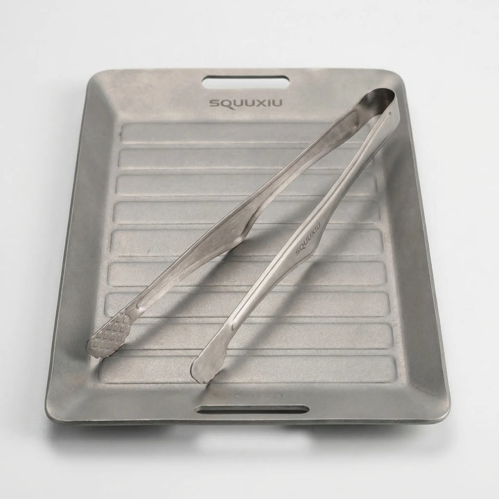 Non-stick outdoor camping grill plate with tongs, essential portable gear for solo adventure cooking.