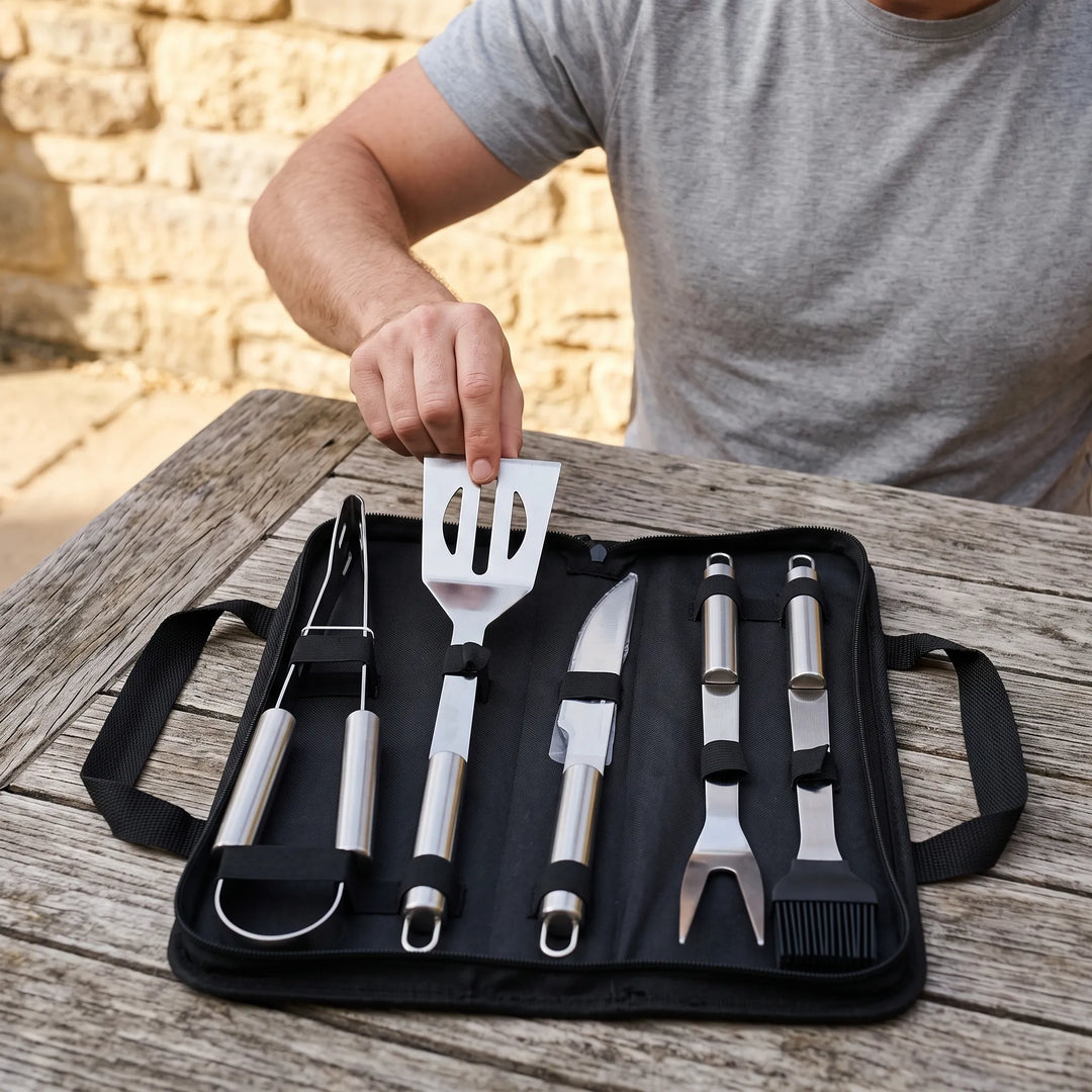 Portable outdoor barbecue grilling tool set with stainless steel utensils for backyard BBQ.