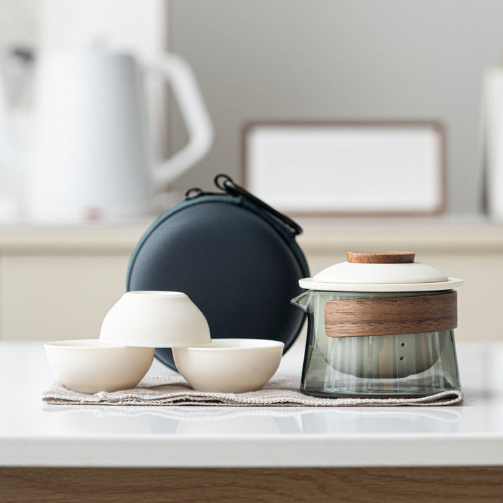 Modern travel ceramic tea set with a sleek glass teapot and three ergonomic cups, designed for convenience.