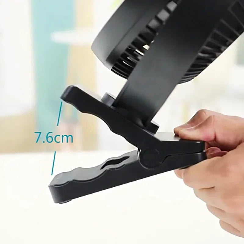 Close-up of a portable rechargeable fan with clip, showing USB charging port and sturdy base