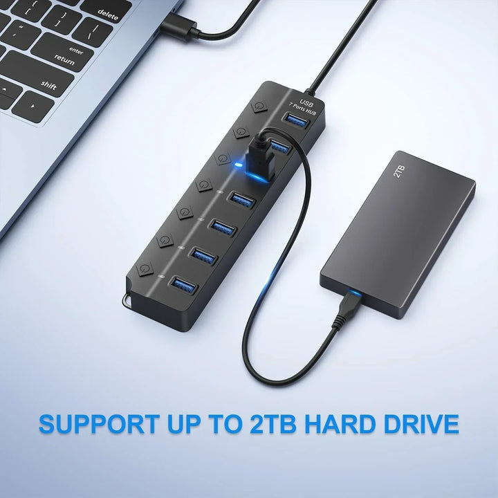 PortMaster 7-Port USB 3.0 hub beside various computer peripherals, emphasizing expanded connectivity