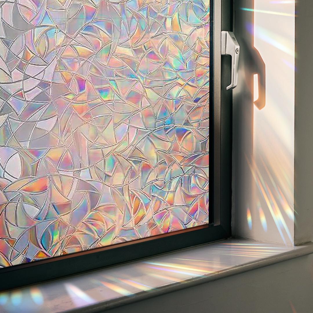 Circular rainbow prism window decal adhering to glass, generating vivid light patterns on an interior wall.