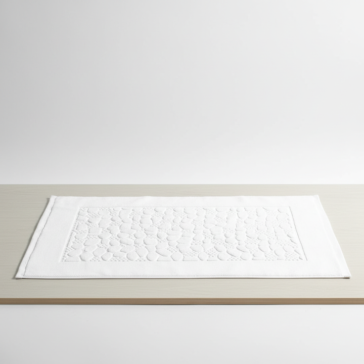 Absorbent rectangular cotton bath mat with subtle geometric pattern, ideal for a comfortable bathroom.