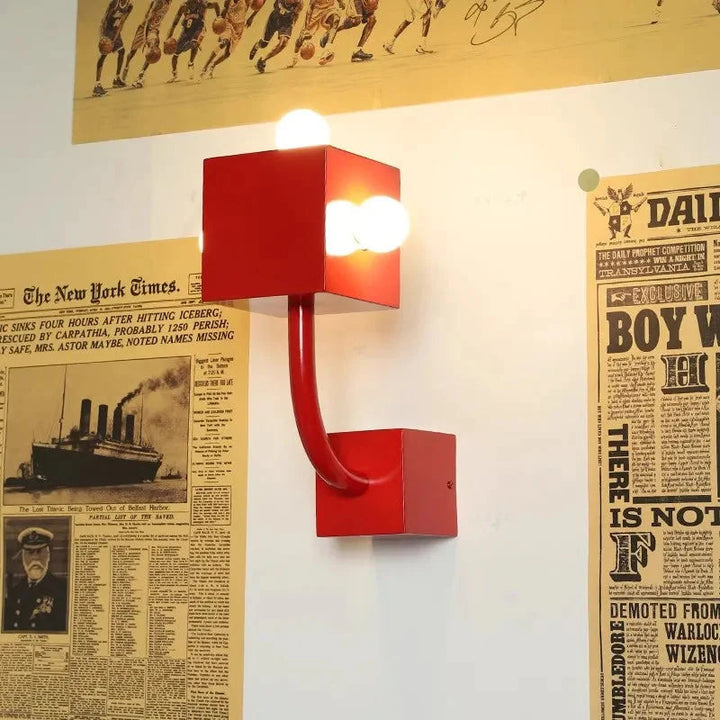 Stylish red wall sconce with three bulbs featuring a geometric design, perfect modern decorative fixture