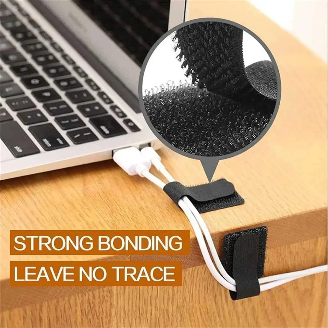 White self-adhesive wire management straps adhering to a smooth desk surface, holding charging cables
