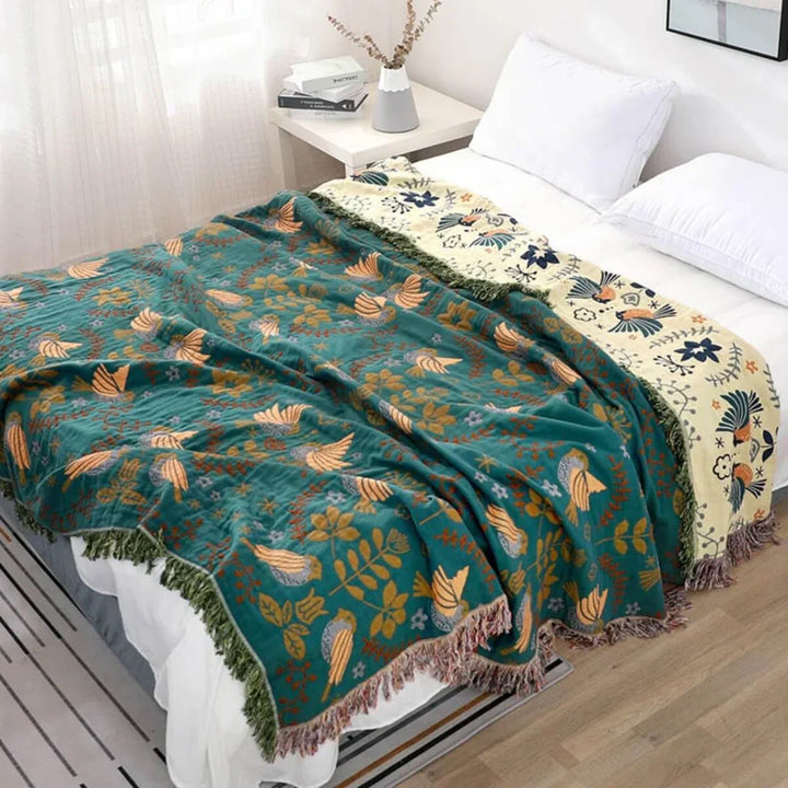 Reversible cotton blanket with Scandinavian bird and floral pattern, ideal as a sofa throw or home decor.