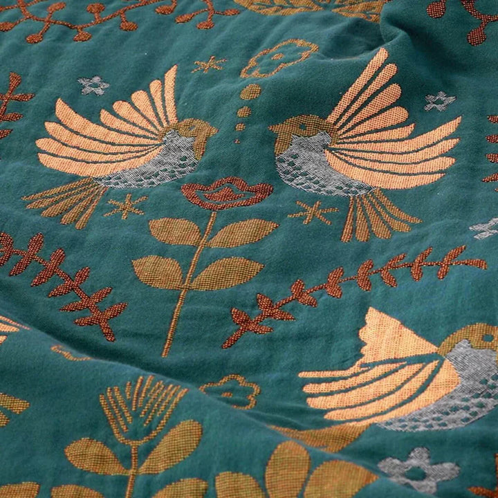 Close-up of soft, reversible cotton throw blanket with detailed Scandinavian bird pattern, perfect for Nordic decor.