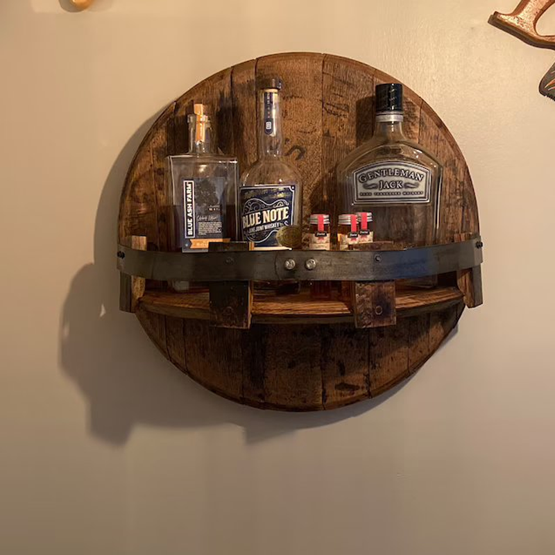 Rustic bourbon barrel shelf, wall-mounted, with metal bands for home bar or kitchen storage.