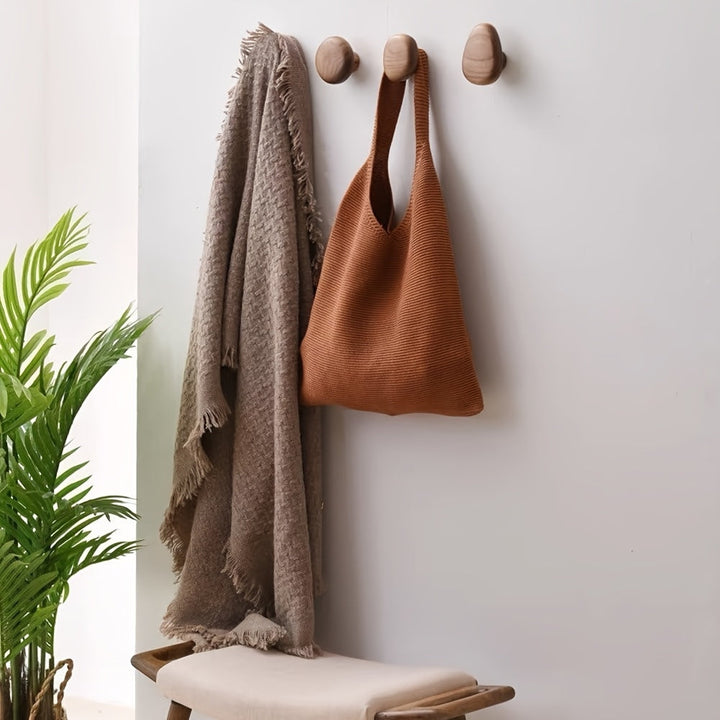 Stylish natural wood pebble hooks for coats, towels, or bags. Modern wall organization and home decor.