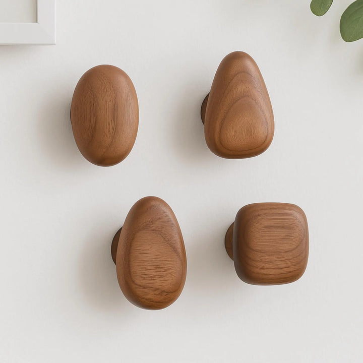 Unique pebble-shaped wooden wall hooks in natural wood, perfect for decorative and functional home organization.