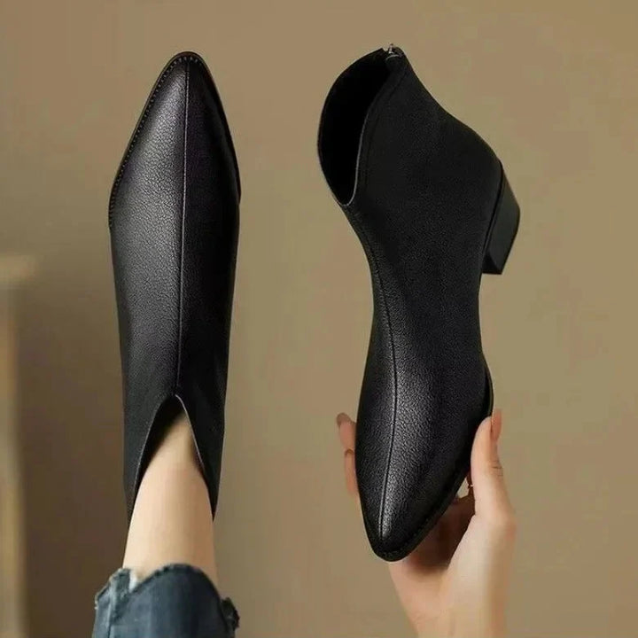 Side profile of elegant women's pointed toe ankle boots, highlighting the low heel and slip-on design.