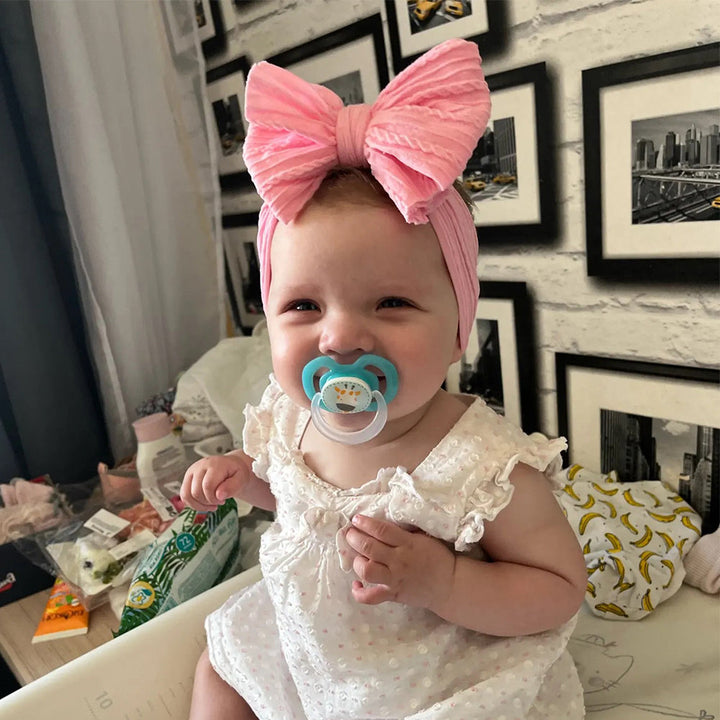 Soft pink nylon bow headband for infants, a cute children's accessory.