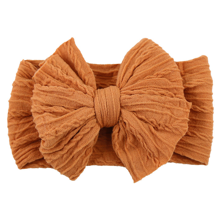 Newborn wearing a delicate cream nylon bow headband, sweet baby fashion.