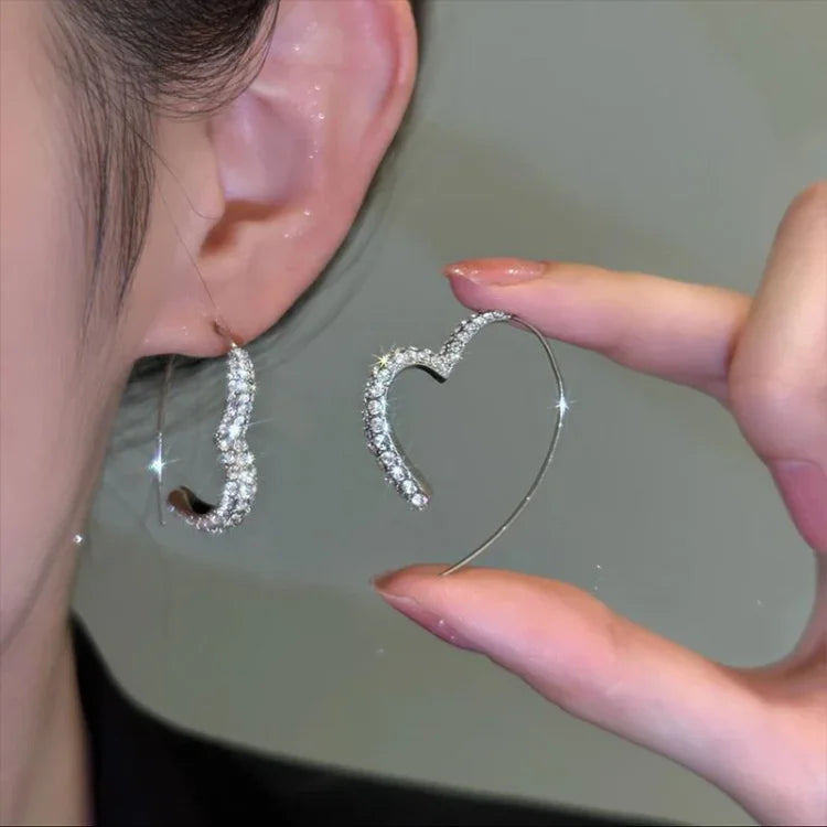 Women's elegant silver heart earrings with sparkling zirconia stones. A beautiful jewelry accessory.