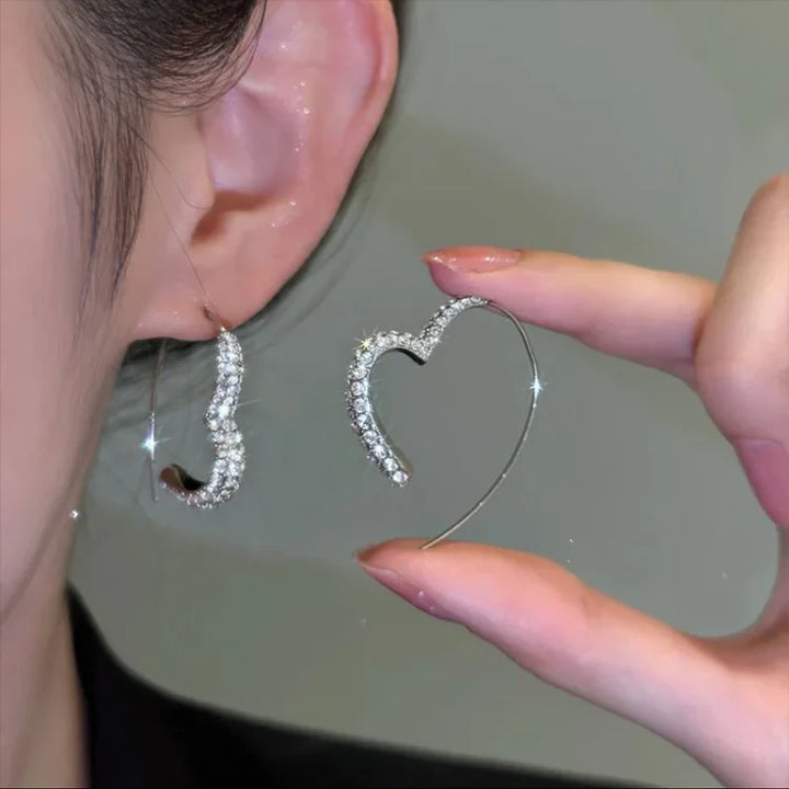 Women's elegant silver heart earrings with sparkling zirconia stones. A beautiful jewelry accessory.