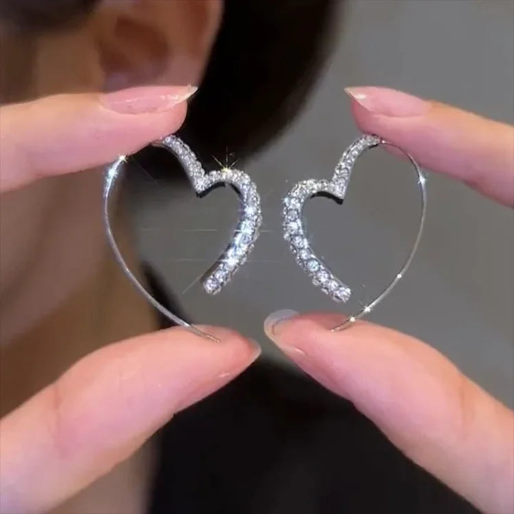 Close-up of dazzling zirconia heart earrings for women. Silver-plated, sparkling, and elegant jewelry.