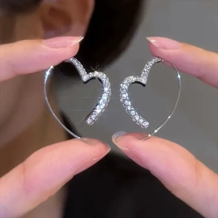 Close-up of dazzling zirconia heart earrings for women. Silver-plated, sparkling, and elegant jewelry.
