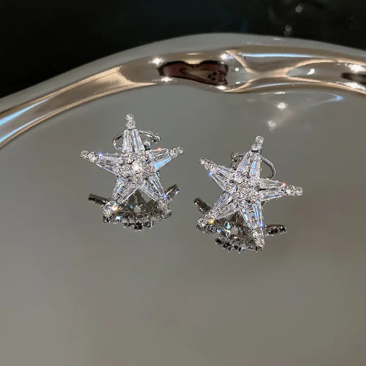 Close-up of women's silver zirconia star earrings and ear cuff. Celestial jewelry, adding a sparkling, versatile touch.