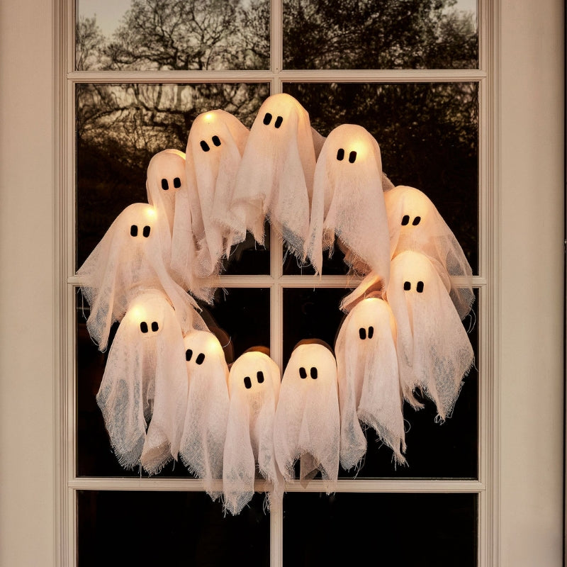 Spooky Halloween ghost wreath with white fabric ghosts, black branches, and warm LED lights, perfect for front door decor.