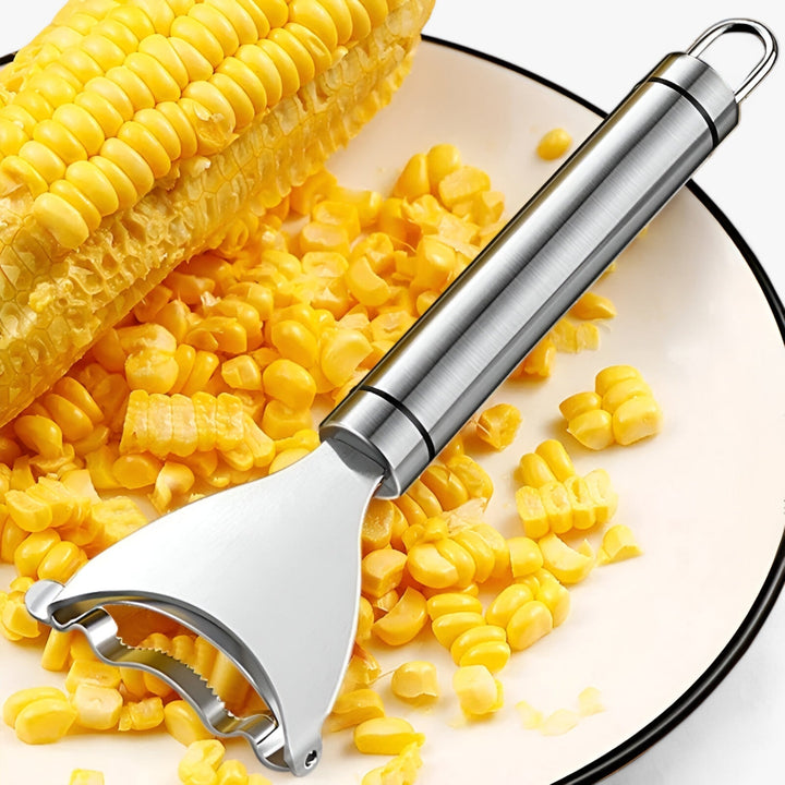 Corn stripper in action: A hand holds the stainless steel corn peeler, effortlessly removing kernels from a fresh cob.