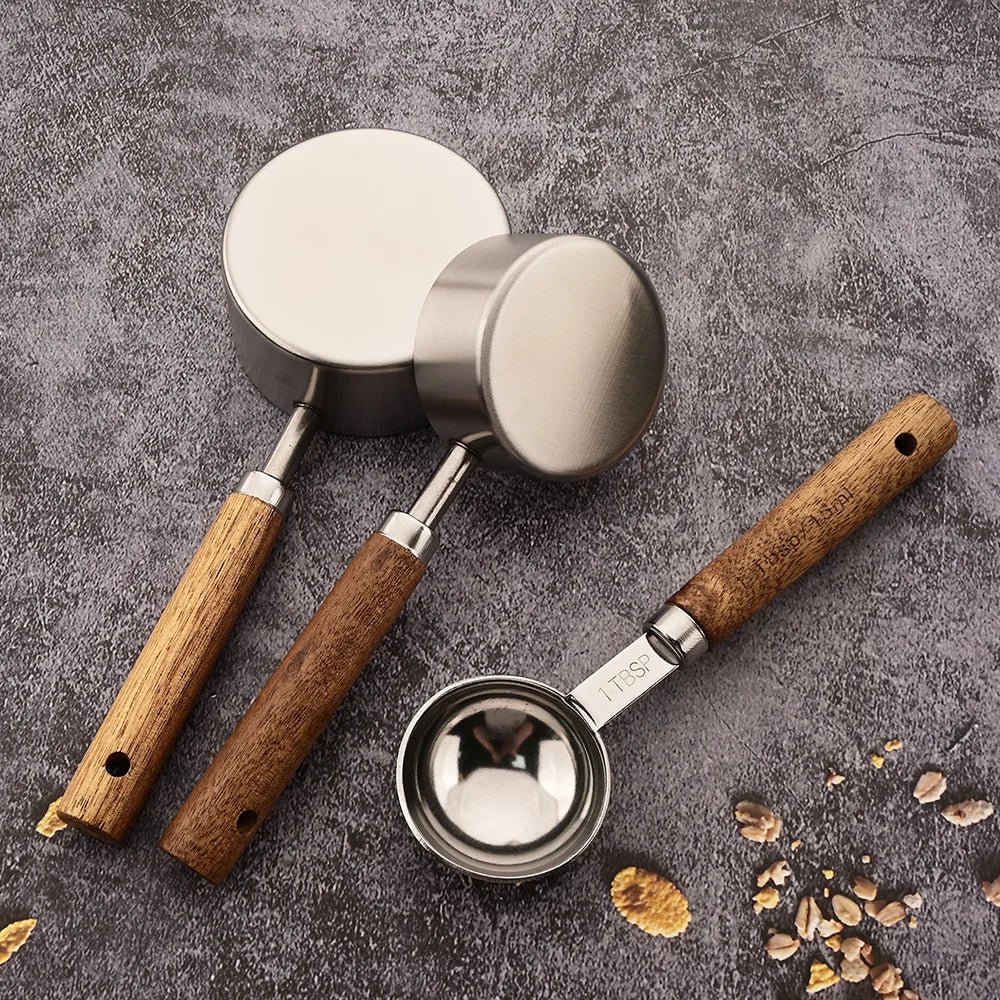Close-up of a stainless steel measuring spoon set, showcasing smooth wood handles & precise markings.