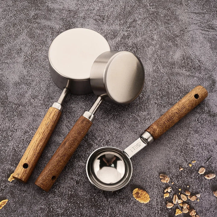 Close-up of a stainless steel measuring spoon set, showcasing smooth wood handles & precise markings.