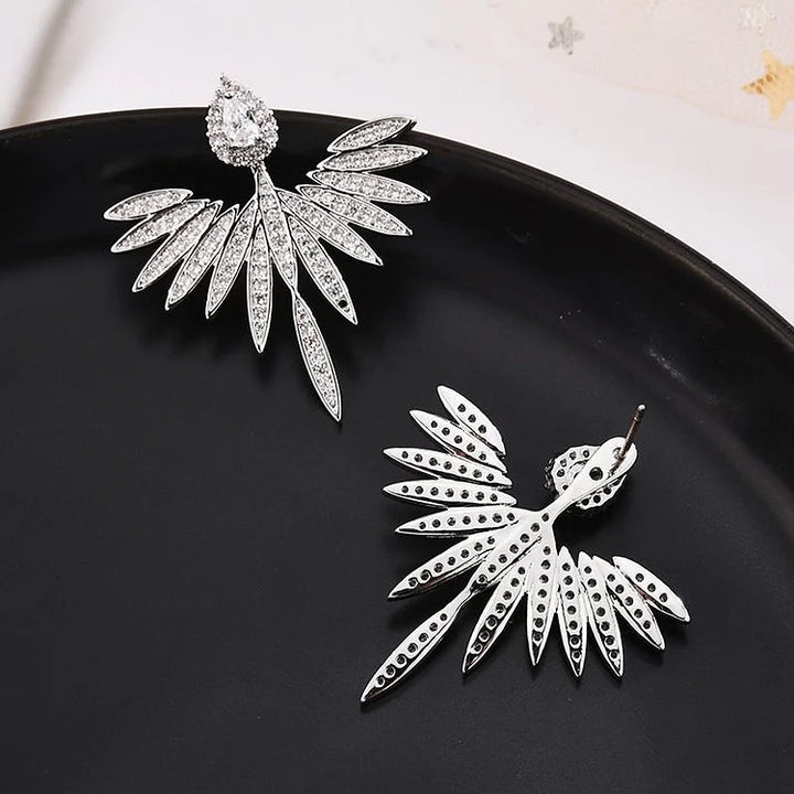 Close-up of women's sterling silver angel wing earrings with shimmering zirconia accents.
