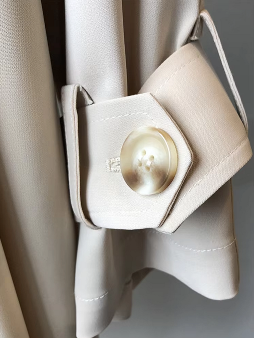 Sophisticated women's double-breasted waterproof trench coat in neutral color, essential for elegant business casual outfits.