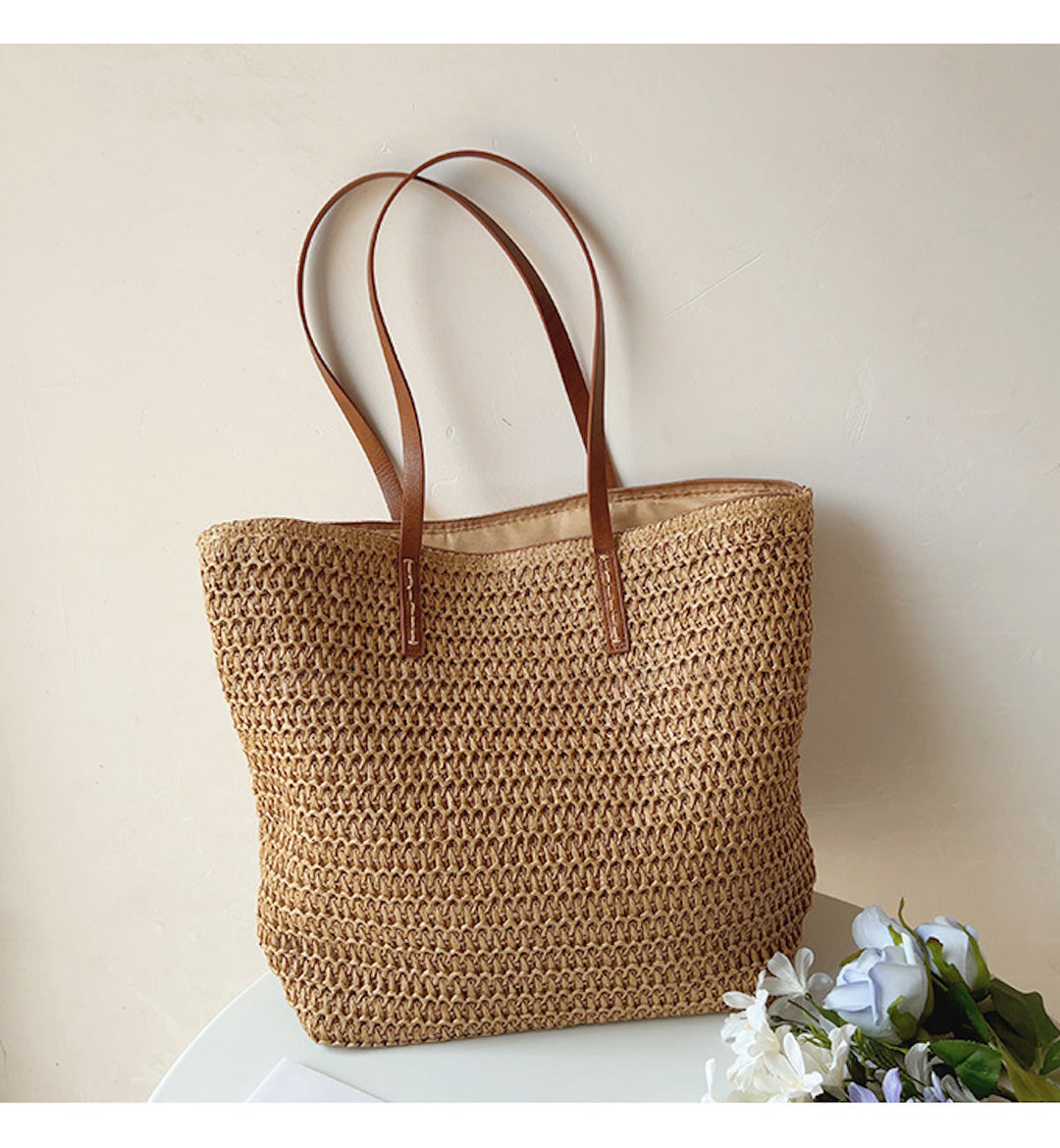 Stylish women's rattan woven tote bag with durable brown leather shoulder straps, perfect for summer.