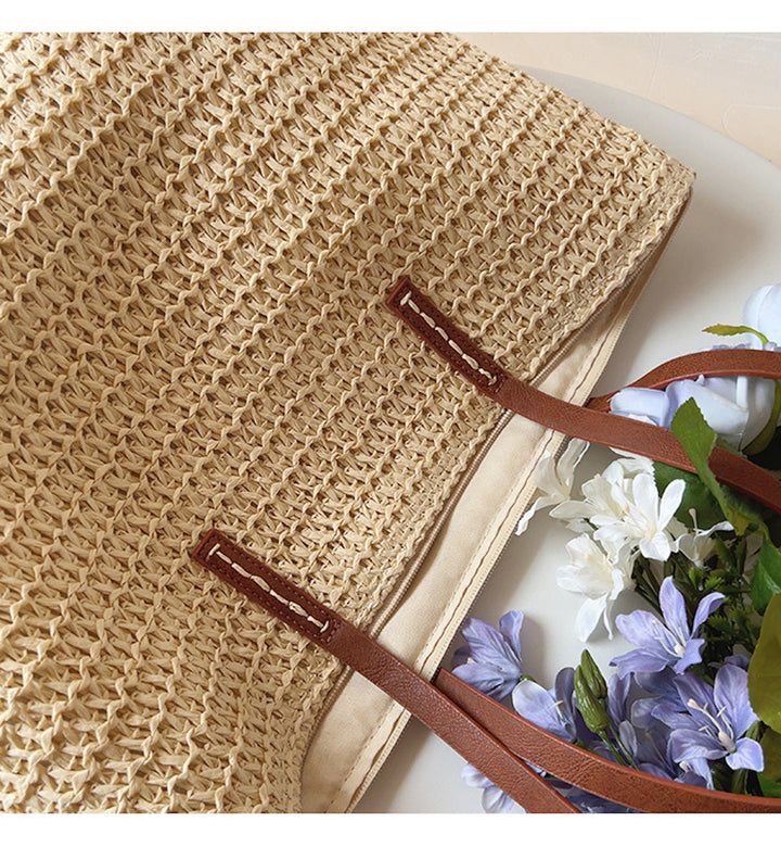 Spacious women's straw rattan tote bag with sturdy leather straps, an ideal companion for beach trips or city strolls.