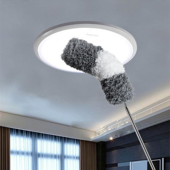 Fully extended telescoping duster reaching a high ceiling corner for thorough dust and cobweb removal.