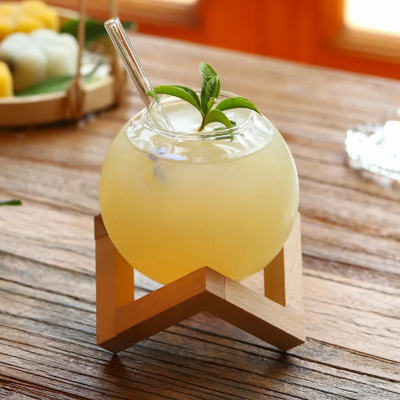 Unique moon ball drink glass with a sleek spherical design and elegant wooden base, perfect for modern home decor.