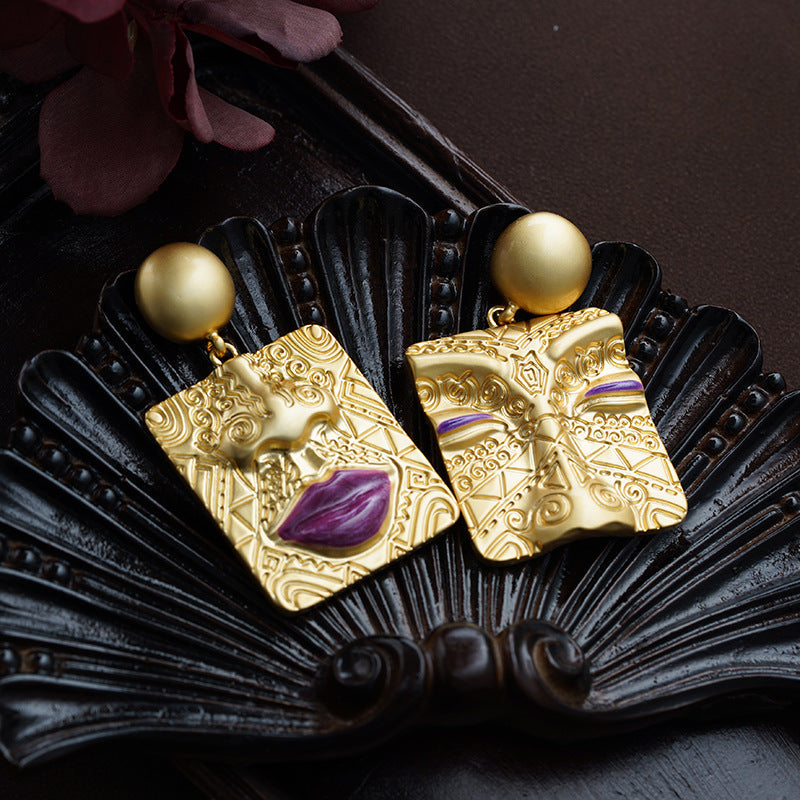 Detailed view of women's gold plated asymmetrical retro earrings, unique statement jewelry.
