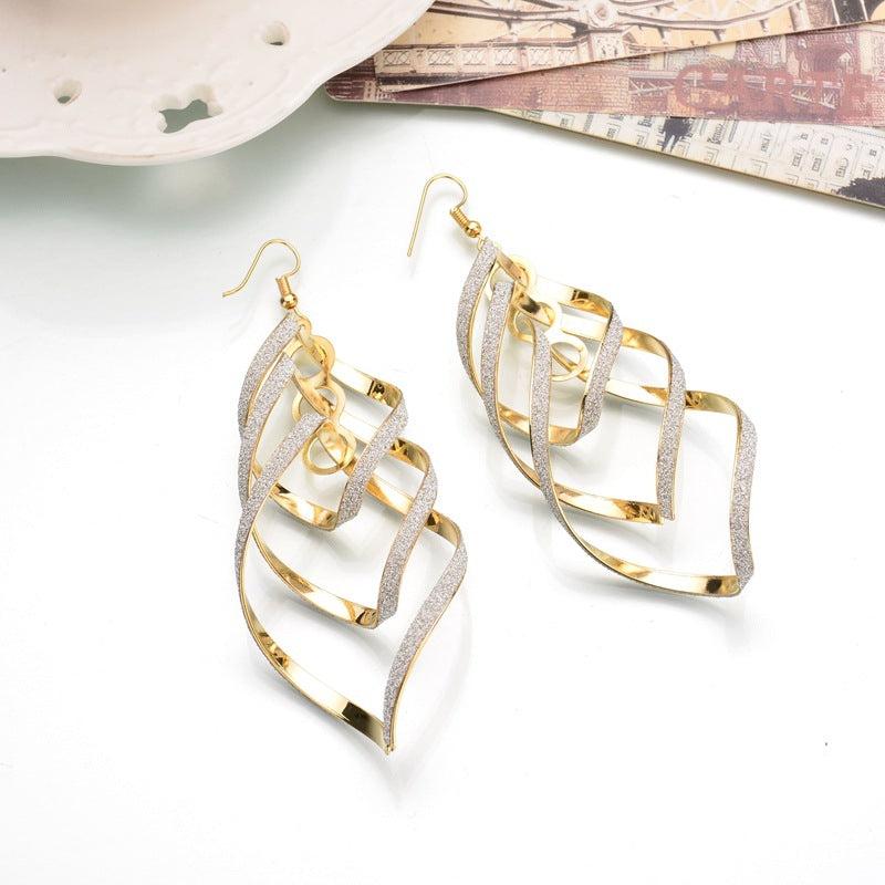 Unique women's golden spiral statement earrings. Dangle design, perfect for fashion-forward looks.