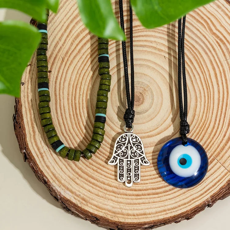 Versatile unisex layered necklace set with symbolic pendants: evil eye, Hamsa hand, and a single pearl.